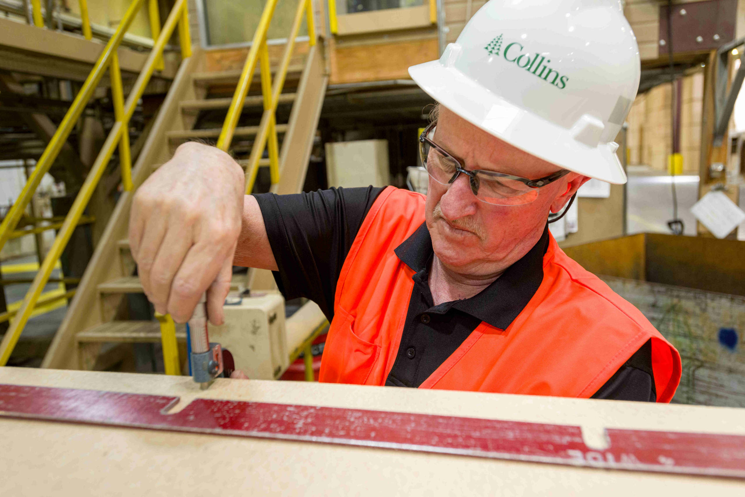 A Collins employee in PPE testing particleboard